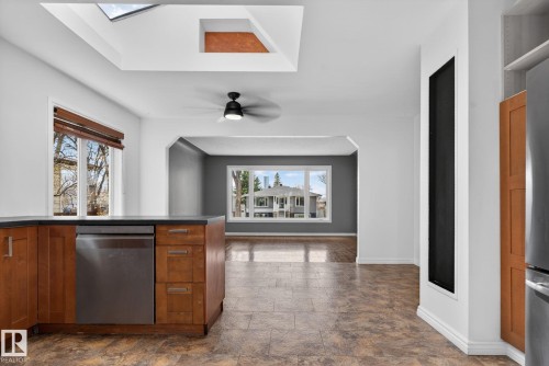 Kitchen area featuring wood-finish cabinetry, a stainless steel dishwasher, and a dark countertop - 10409 83 Street, Edmonton, AB - Indoor