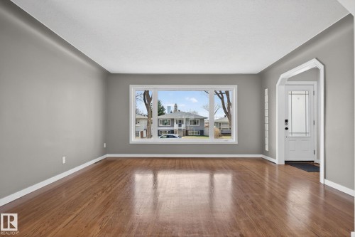 Spacious room featuring wood-finish flooring, light gray walls, and white trim - 10409 83 Street, Edmonton, AB - Indoor