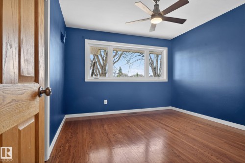 Expansive wood-finish flooring complemented by a ceiling fan with integrated lighting - 10409 83 Street, Edmonton, AB - Indoor Photo Showing Other Room