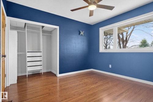 Room with wood-finish flooring, a ceiling fan, and a wide window with white trim - 10409 83 Street, Edmonton, AB - Indoor Photo Showing Other Room