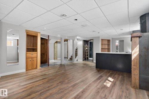 Spacious lower level featuring wood-finish flooring, a built-in bar with a light-toned countertop, recessed lighting, and a drop ceiling - 10409 83 Street, Edmonton, AB - Indoor Photo Showing Other Room