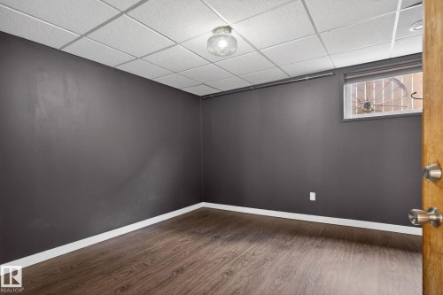 Room featuring dark gray walls, wood-finish flooring, and white baseboards - 10409 83 Street, Edmonton, AB - Indoor Photo Showing Other Room