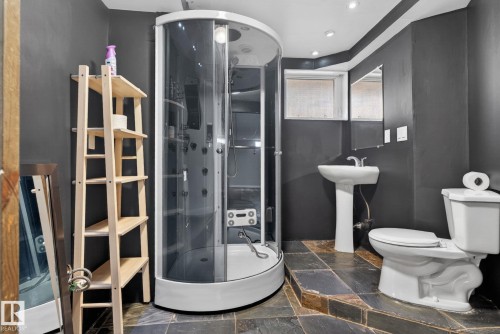 Bathroom featuring a curved glass shower enclosure with multiple spray jets, a pedestal sink, and a toilet - 10409 83 Street, Edmonton, AB - Indoor Photo Showing Bathroom