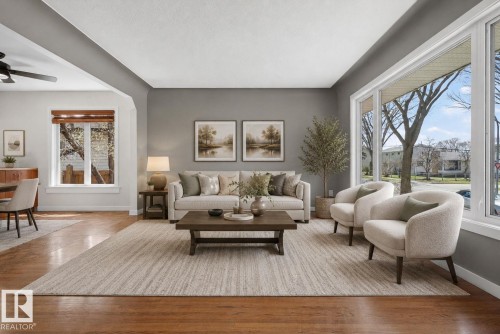 Living area featuring expansive picture windows, hardwood flooring, a recessed ceiling, and an arched entryway - 10409 83 Street, Edmonton, AB - Indoor Photo Showing Living Room