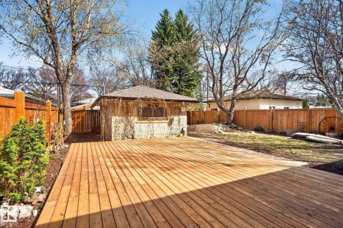 Expansive wood deck with a privacy fence, mature trees, and a detached outbuilding - 10409 83 Street, Edmonton, AB - Outdoor With Deck Patio Veranda With Backyard