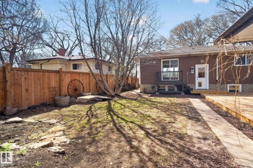 Rear exterior with a brown siding facade, a wood deck, and a concrete pathway - 10409 83 Street, Edmonton, AB - Outdoor