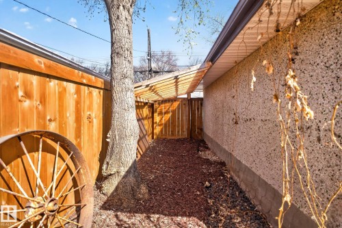 Rear exterior pathway featuring a wood slat pergola, a wood plank fence, and a stucco-finish wall - 10409 83 Street, Edmonton, AB - Outdoor