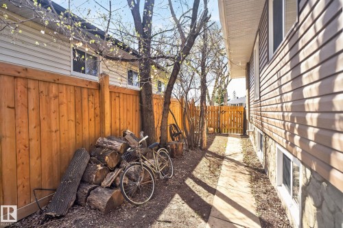 Side yard featuring a concrete pathway, a wood privacy fence, and a gate providing property access - 10409 83 Street, Edmonton, AB - Outdoor