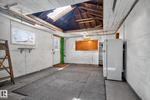 Garage interior featuring concrete walls, a white window, and an exposed wood ceiling with an open skylight - 10409 83 Street, Edmonton, AB - Indoor Photo Showing Garage