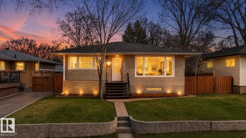 Stucco exterior residence featuring a prominent picture window, dark shingle roof, and a concrete pathway leading to the front entry - 10409 83 Street, Edmonton, AB - Outdoor With Deck Patio Veranda