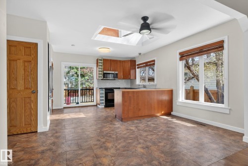 Kitchen and dining area featuring wood-finish flooring, a skylight, and a ceiling fan - 10409 83 Street, Edmonton, AB - Indoor Photo Showing Kitchen