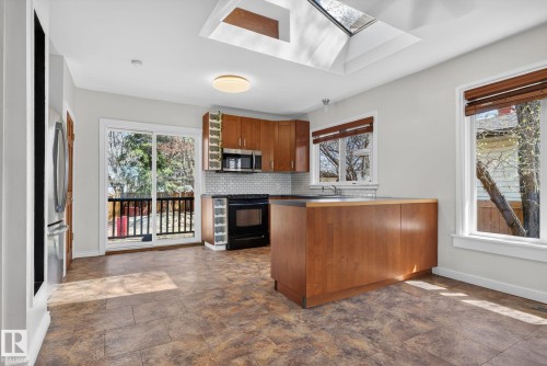 Kitchen featuring wood-finish cabinetry, a central island, and a subway tile backsplash - 10409 83 Street, Edmonton, AB - Indoor Photo Showing Kitchen