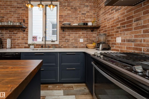Beautifully updated kitchen with quartz counters, gas stove, and industrial-style lighting - 10956 81 Avenue, Edmonton, AB - Indoor Photo Showing Kitchen With Double Sink