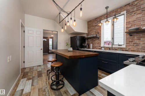 Beautifully updated kitchen with quartz counters, gas stove, and industrial-style lighting - 10956 81 Avenue, Edmonton, AB - Indoor