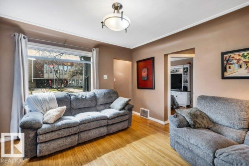 Bright living area featuring wood-finish flooring, a large picture window, and crown molding - 11445 68 Street, Edmonton, AB - Indoor Photo Showing Living Room