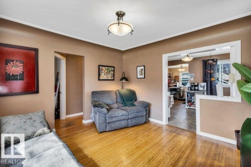 Hardwood-finish flooring extending into an open archway - 11445 68 Street, Edmonton, AB - Indoor Photo Showing Living Room