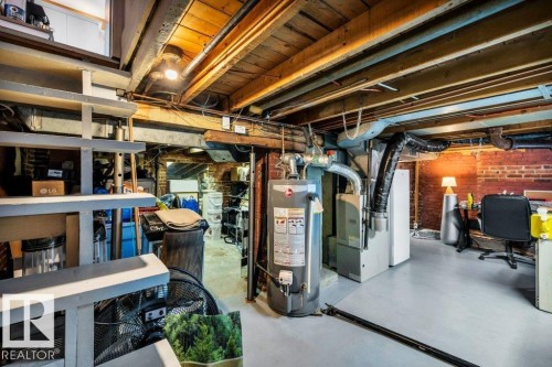 Basement area featuring exposed wood ceiling joists, painted concrete flooring, and brick wall accents - 11445 68 Street, Edmonton, AB - Indoor Photo Showing Basement