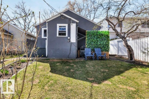Rear exterior featuring a grey stucco finish, white trim windows, and a partially fenced yard - 11445 68 Street, Edmonton, AB - Outdoor
