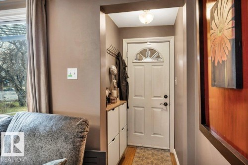 Entryway featuring a white paneled door with an arched glass insert, black hardware, and an overhead flush-mount light fixture - 11445 68 Street, Edmonton, AB - Indoor