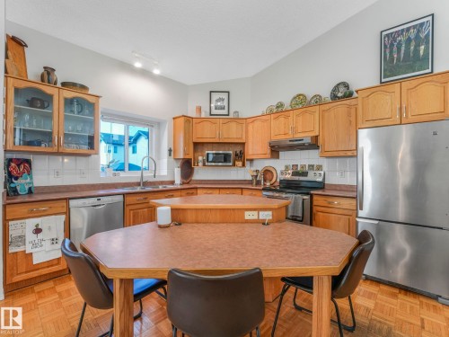 The kitchen features wood cabinetry, a stainless steel refrigerator, and a built-in oven and stovetop - 308 Beringer Crescent, Edmonton, AB - Indoor