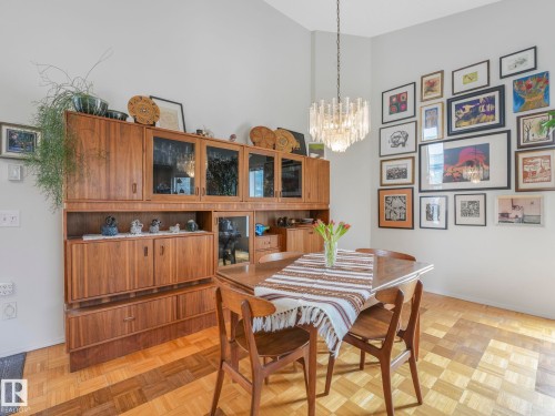 Dining area featuring parquet flooring, a modern chandelier, and a built-in wooden display cabinet - 308 Beringer Crescent, Edmonton, AB - Indoor Photo Showing Dining Room
