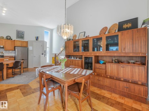 This open-concept living space features a vaulted ceiling, a statement chandelier, and varied hardwood flooring - 308 Beringer Crescent, Edmonton, AB - Indoor Photo Showing Dining Room