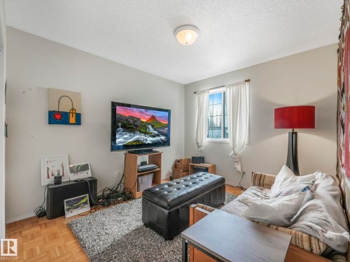 Living area featuring parquet wood flooring and a window with white curtains - 308 Beringer Crescent, Edmonton, AB - Indoor Photo Showing Living Room