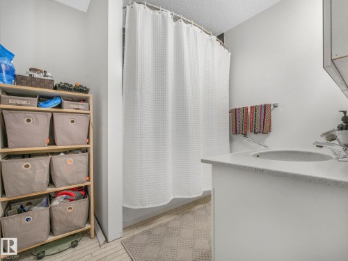 The bathroom features a vanity with a sink, a shower with a white curtain, and light-toned walls - 308 Beringer Crescent, Edmonton, AB - Indoor Photo Showing Bathroom