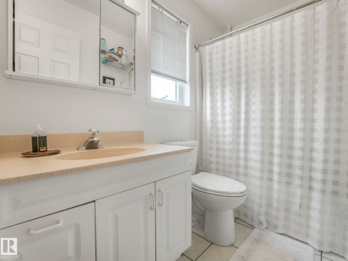 This bathroom features a vanity with white cabinetry and a light-colored countertop, a toilet, and a window with blinds - 308 Beringer Crescent, Edmonton, AB - Indoor Photo Showing Bathroom