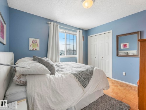 This room features a window providing natural light, a closet with bi-fold doors, and parquet flooring - 308 Beringer Crescent, Edmonton, AB - Indoor Photo Showing Bedroom