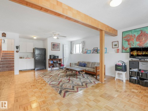 Living space featuring light wood parquet flooring and a partial kitchen with white cabinetry and a black refrigerator - 308 Beringer Crescent, Edmonton, AB - Indoor