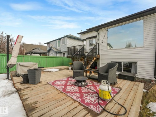 The property features an outdoor wood deck, a large window, and a green fence - 308 Beringer Crescent, Edmonton, AB - Outdoor With Deck Patio Veranda With Exterior
