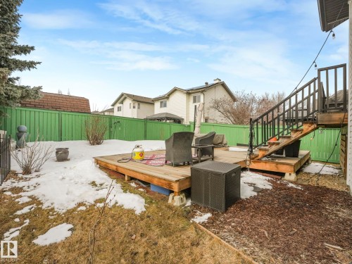 The property features an extensive outdoor deck with stairs, surrounded by a green fence and mature trees - 308 Beringer Crescent, Edmonton, AB - Outdoor With Deck Patio Veranda With Backyard