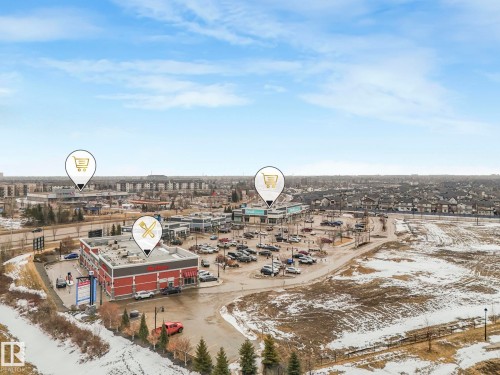 Aerial view showcasing the surrounding commercial and residential areas, featuring retail buildings, parking lots, and undeveloped land - 308 Beringer Crescent, Edmonton, AB - Outdoor With View