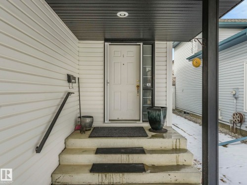 The property features an entryway with concrete steps, a white paneled door, and a black handrail - 308 Beringer Crescent, Edmonton, AB - Outdoor With Exterior