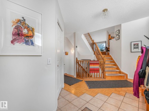 Entryway featuring a staircase with wood railings and treads, and a mix of tile and wood flooring - 308 Beringer Crescent, Edmonton, AB - Indoor Photo Showing Other Room