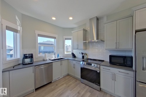 Kitchen featuring light-toned cabinetry, stainless steel appliances, a tile backsplash, recessed lighting, and wood-finish flooring - 33 150 Everitt Dr, St. Albert, AB - Indoor Photo Showing Kitchen