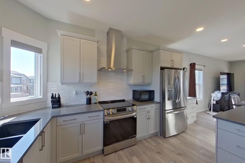 Modern kitchen featuring light cabinetry, stainless steel appliances, a white tile backsplash, and light wood-finish flooring - 33 150 Everitt Dr, St. Albert, AB - Indoor Photo Showing Kitchen With Double Sink