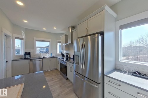 Modern kitchen featuring light cabinetry, stainless steel appliances, durable countertops, wood-finish flooring, and ample natural light from multiple windows - 33 150 Everitt Dr, St. Albert, AB - Indoor Photo Showing Kitchen With Upgraded Kitchen