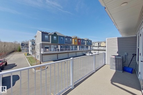 Private balcony with white railing, overlooking a paved parking area and multi-story townhome buildings - 33 150 Everitt Dr, St. Albert, AB - Outdoor With Exterior