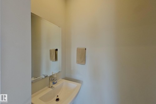 Pedestal sink with chrome faucet, complemented by a frameless wall mirror - 33 150 Everitt Dr, St. Albert, AB - Indoor Photo Showing Bathroom