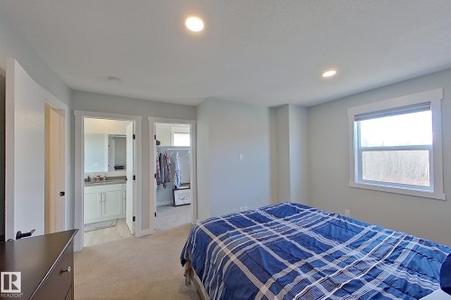 Carpeted bedroom with recessed lighting, a large window, and direct access to a separate bathroom and walk-in closet - 33 150 Everitt Dr, St. Albert, AB - Indoor Photo Showing Bedroom