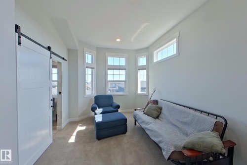 Bright room featuring a prominent bay window, white trim, and a white barn door with black hardware - 33 150 Everitt Dr, St. Albert, AB - Indoor