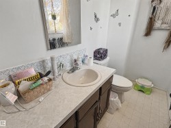 Bathroom featuring a window with natural light, vanity with integrated sink, dark wood-finish cabinetry, and patterned wallpaper border - 