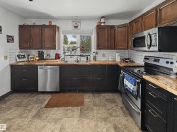 Functional kitchen featuring wood-finish countertops, subway tile backsplash, and stainless steel appliances - 