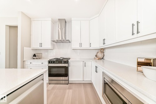 Modern kitchen featuring white cabinetry, light-colored countertops, and wood-finish flooring - 1603 206 Street, Edmonton, AB - Indoor Photo Showing Kitchen