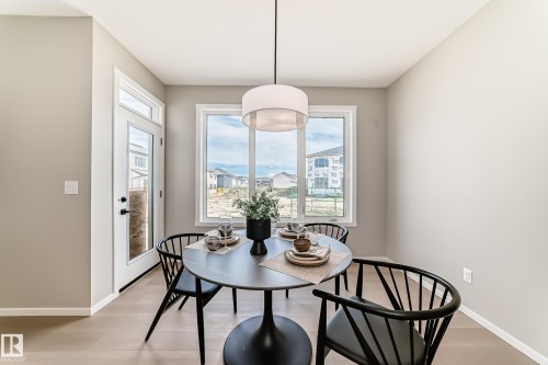 Dining area featuring wood-finish flooring, a large window, and a glass-paneled exterior door - 1603 206 Street, Edmonton, AB - Indoor Photo Showing Dining Room