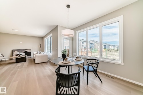 Open-concept living space featuring wood-finish flooring, a large multi-pane window, and light neutral wall tones - 1603 206 Street, Edmonton, AB - Indoor
