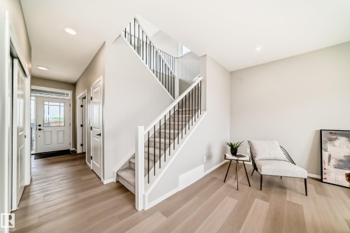 Entryway featuring light wood-finish flooring, a two-story staircase with dark balusters and white handrails, a white paneled door with glass inserts, recessed lighting, and white trim throughout - 1603 206 Street, Edmonton, AB - Indoor Photo Showing Other Room