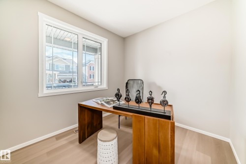 Bright room featuring a large white-framed window, light wood-finish flooring, and neutral wall tones - 1603 206 Street, Edmonton, AB - Indoor Photo Showing Office